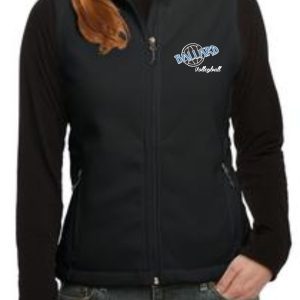 Woman wearing a black zip-up jacket with Ballard Volleyball spirit Ladies Fleece Vest L219 logo on the left chest, hands in pockets.