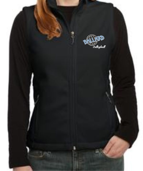 Woman wearing a black zip-up jacket with Ballard Volleyball spirit Ladies Fleece Vest L219 logo on the left chest, hands in pockets.